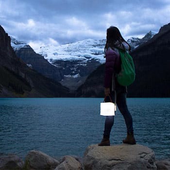 A-bright-solar-lantern-being-held-by-a-woman-looking-out-over-the-sea