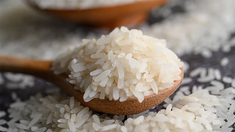 Uncooked rice in a wooden spoon