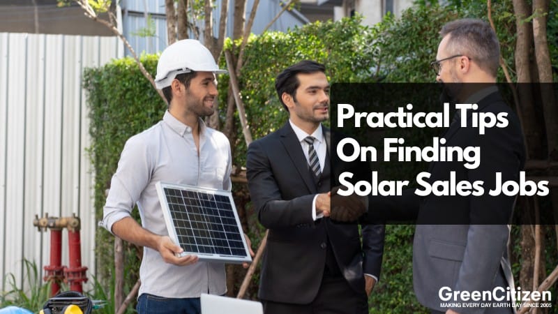 Three men are engaged in a discussion outdoors, with one holding a solar panel and the other two shaking hands, set against a backdrop of greenery and a red fire hydrant.